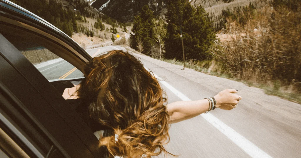 Woman Hanging Out Car Window On A Road Trip